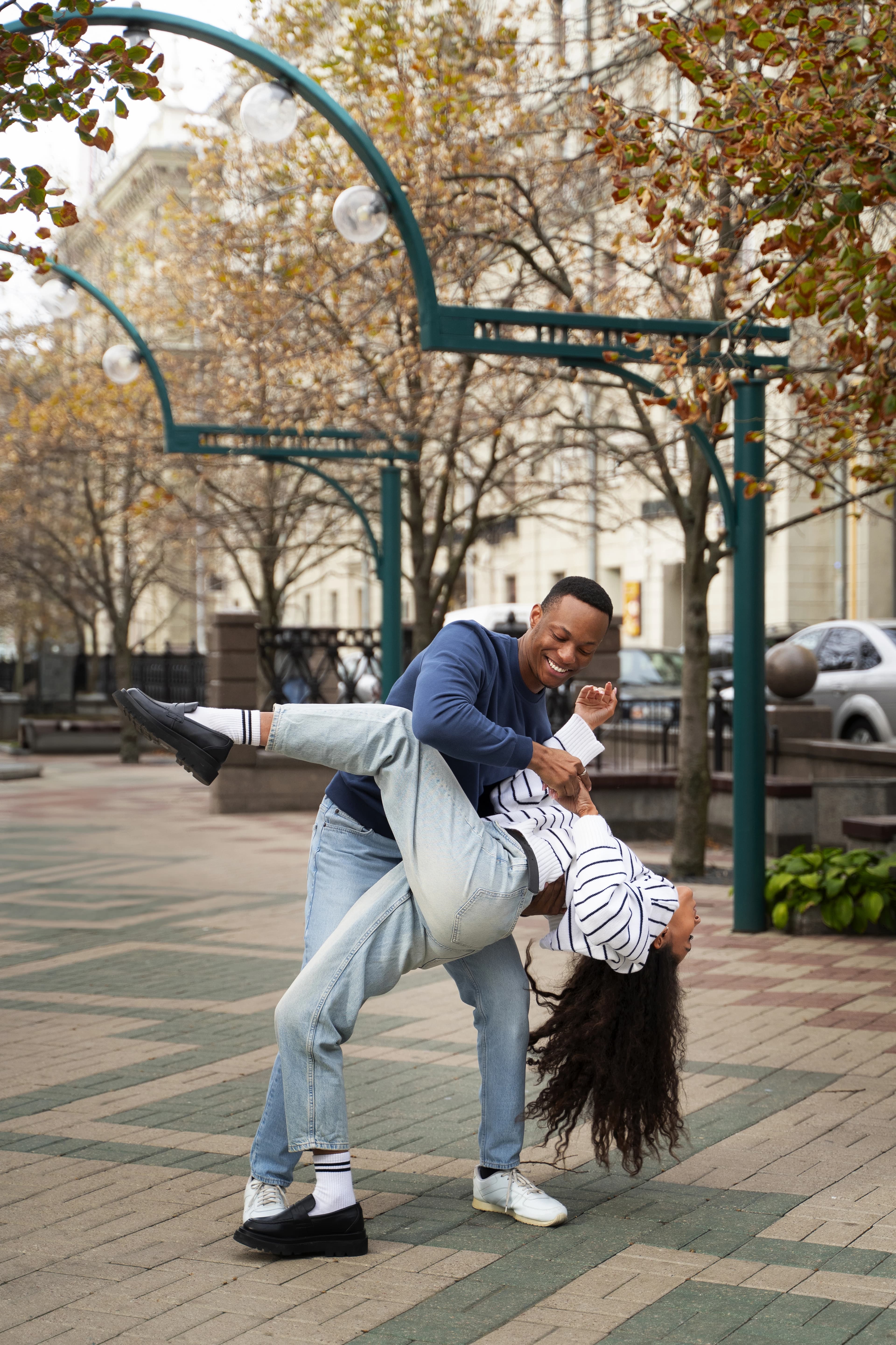 Cinematic photograph of a young couple laughing during a golden hour outdoor shoot, shallow depth of field, warm tones, professional DSLR style.